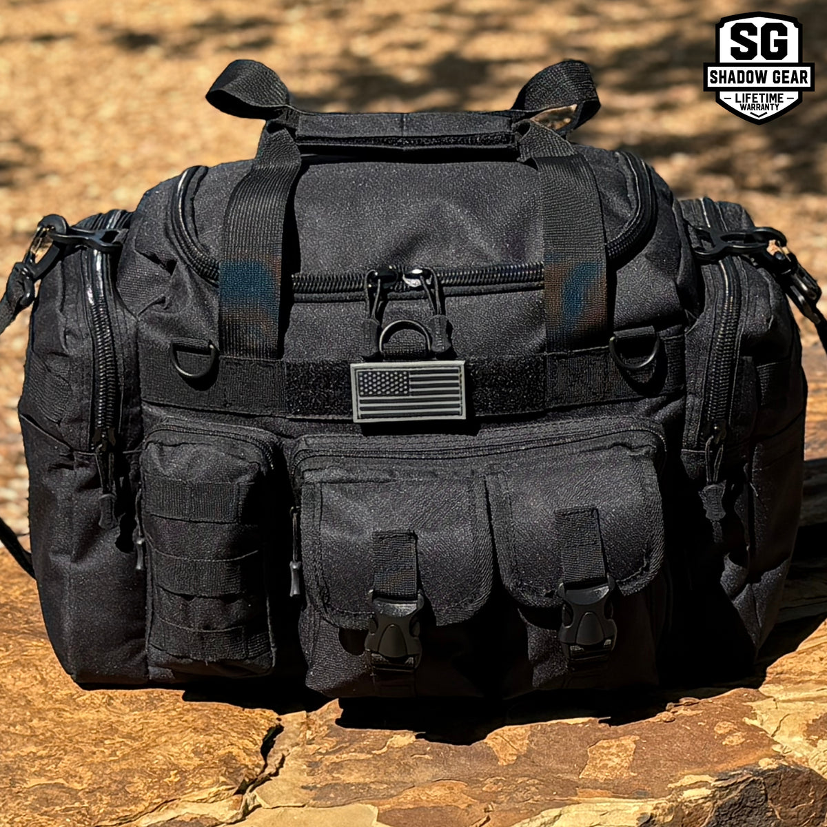 Shadow Gear Traverse 18 42L tactical MOLLE duffel bag in Black on a rock outdoors, with American flag patch