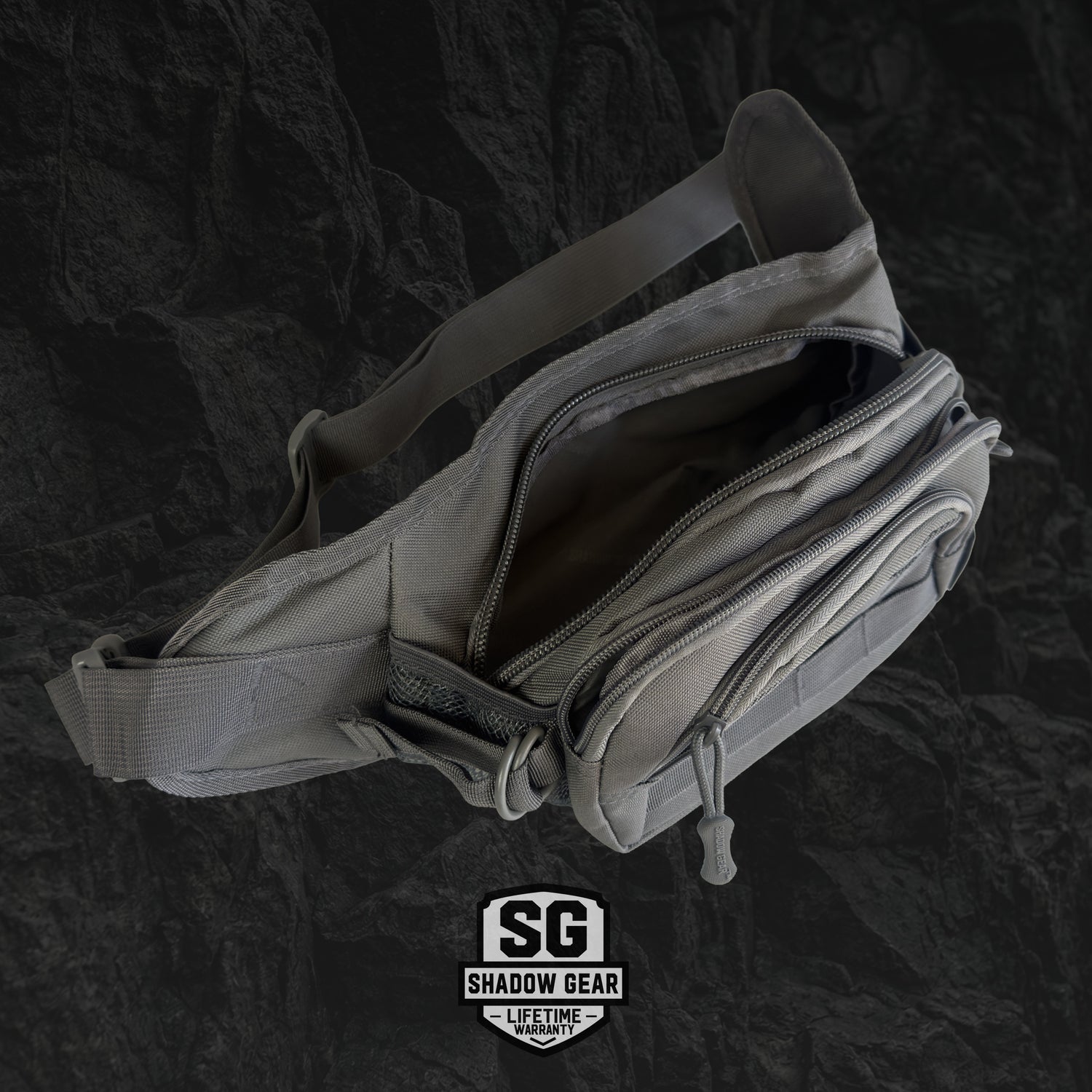Gray waist bag with multiple zippers on a dark textured background, featuring the Shadow Gear logo.