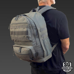Man wearing the Shadow Gear Ridge 39L tactical MOLLE backpack in Charcoal, studio lifestyle shot